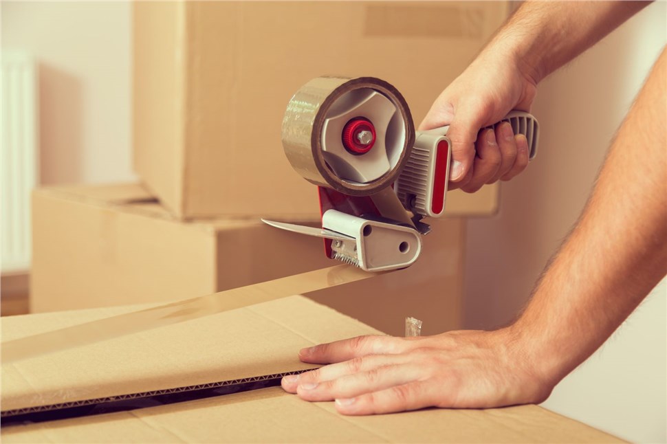 person taping packed moving box
